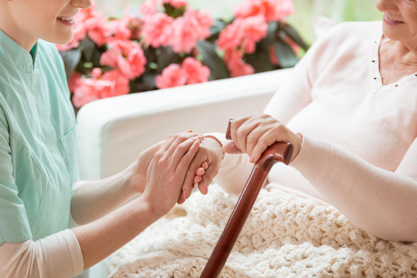 home care worker holding senior woman's hand