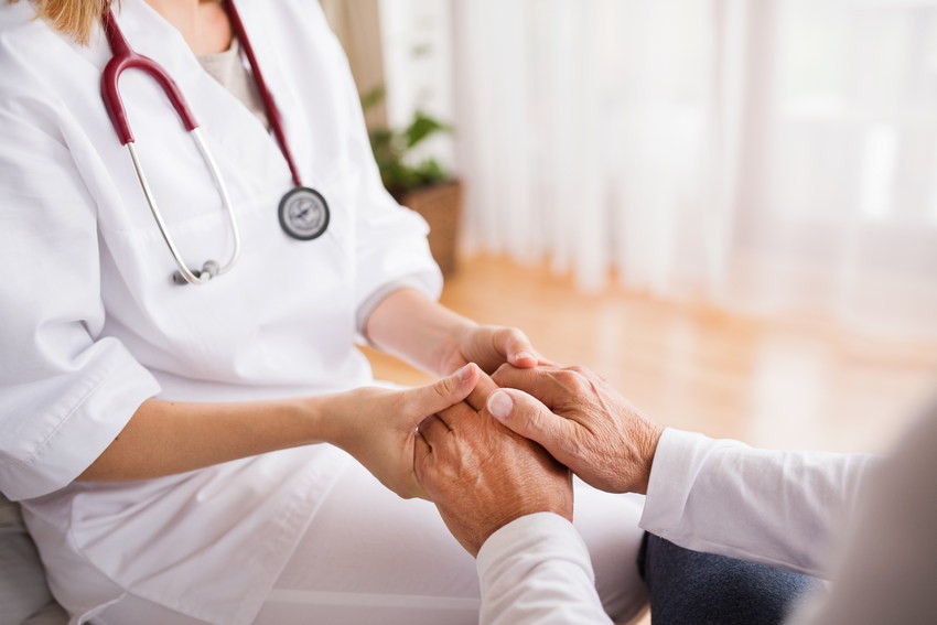 health care worker holding senior man's hands