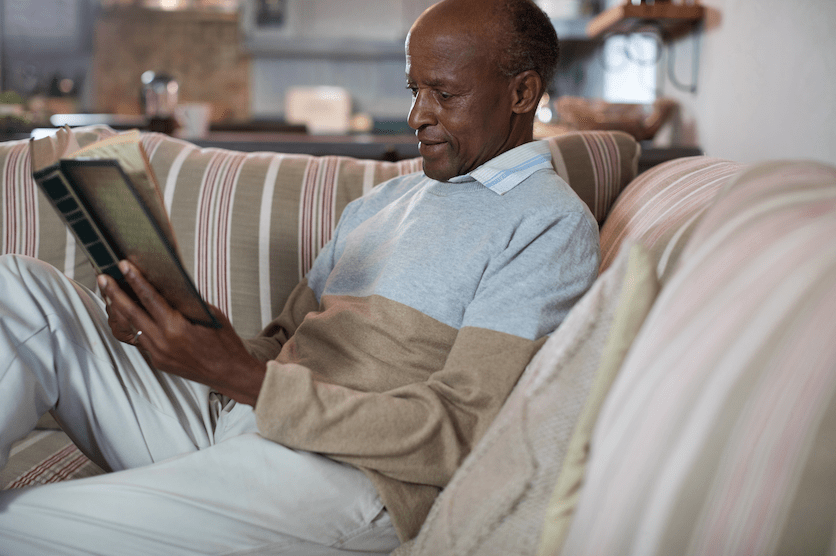 Senior man reading book on sofa