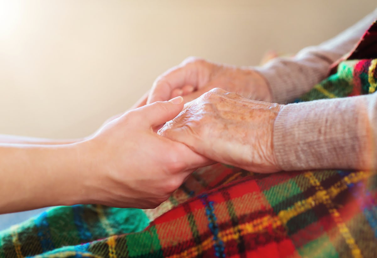 close up of elderly person holding hands with younger person