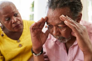 Senior man showing signs of memory loss or confusion while being comforted by a supportive woman.