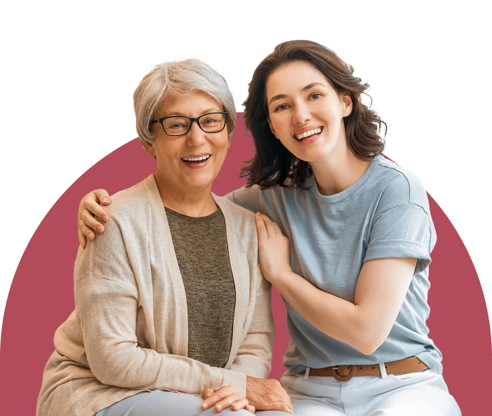 Smiling caregiver and elderly woman sitting together, showing companionship and support.