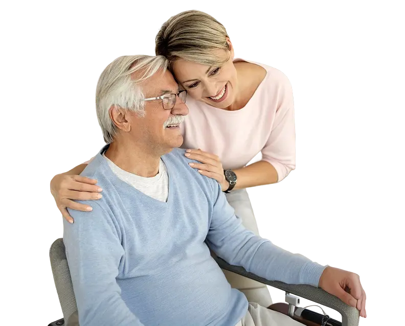 A smiling young woman embracing an elderly man seated in a wheelchair on a white background