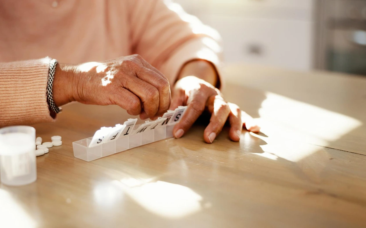 Older adult using a weekly pill organizer